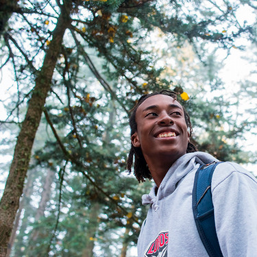 a male student walking past some trees